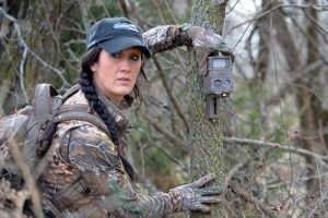 Woman Putting Trail Camera On Tree